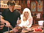Randy Travis cuts the roast beef at their home in Santa Fe, New Mexico, while wife Liv looks on
